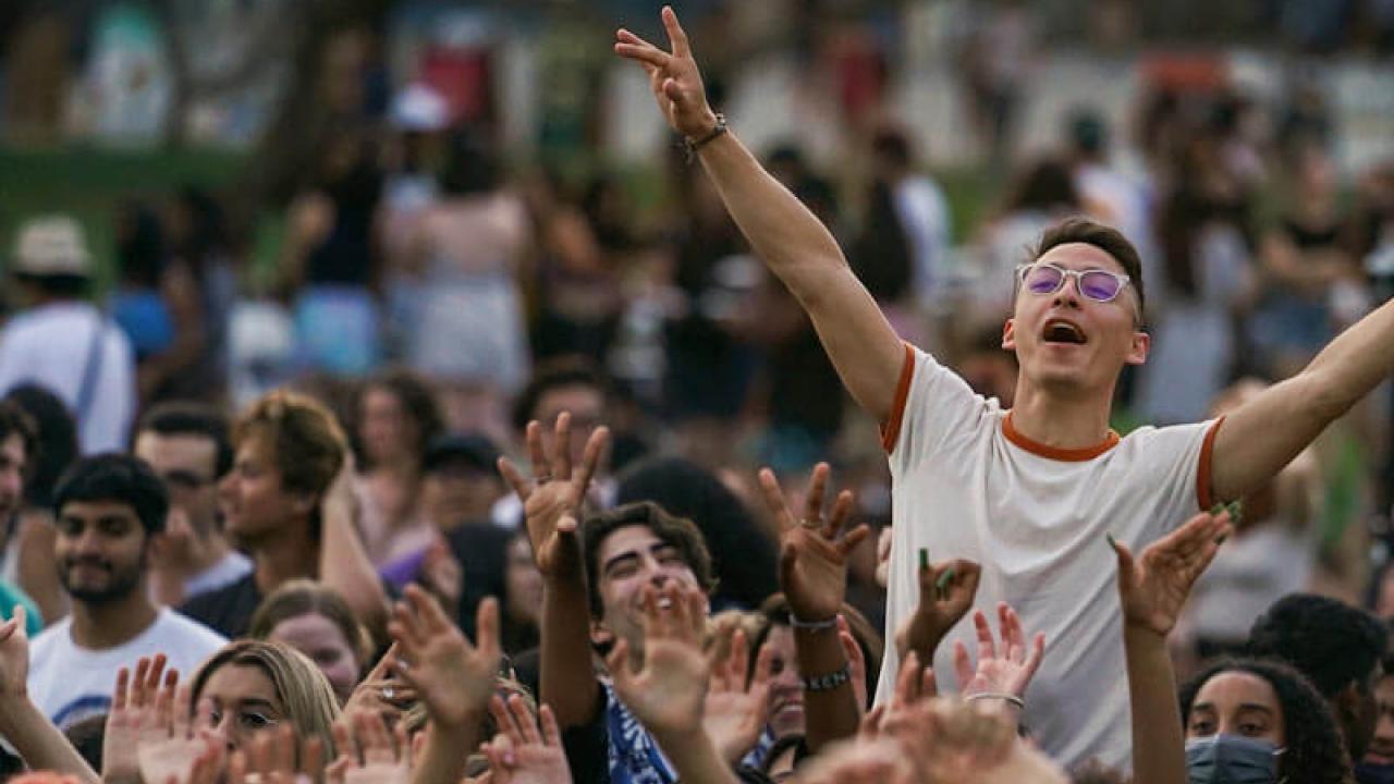 A student cheering above the crowd at the annual Lawntopia event on the Quad at UC Davis