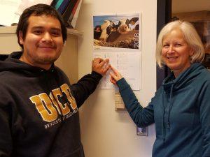 two individuals pointing to a calendar